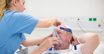 Eine Pflegerin hilft dem Patienten im Schlaflabor des KRH Klinikum Region Hannover seine Atemmaske aufzusetzen
