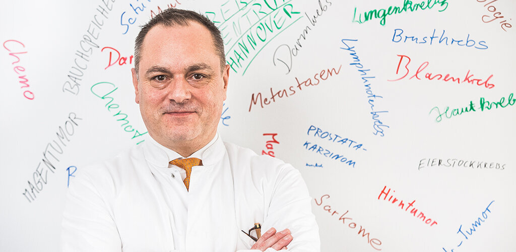 PD Dr. med. Dr. rer. nat. Martin Müller vor Tafel mit verschiedenen Krebsarten